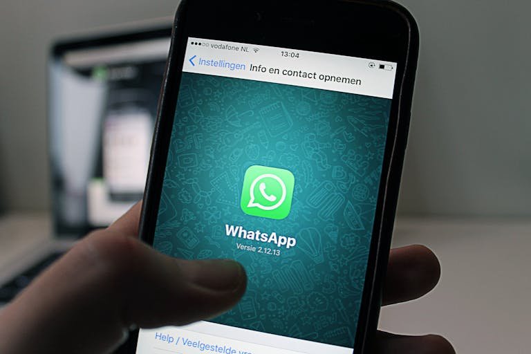 A smartphone displaying the WhatsApp chat application screen held by a person.