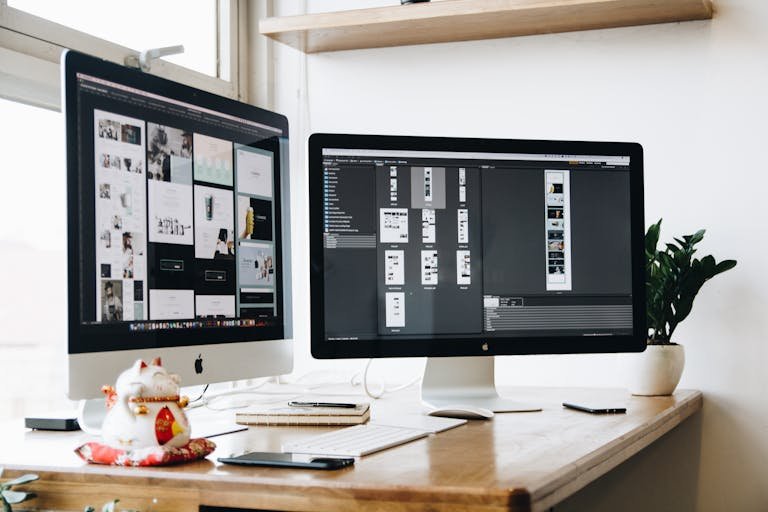 Stylish office workspace featuring dual monitors showing webdesign screens of websites